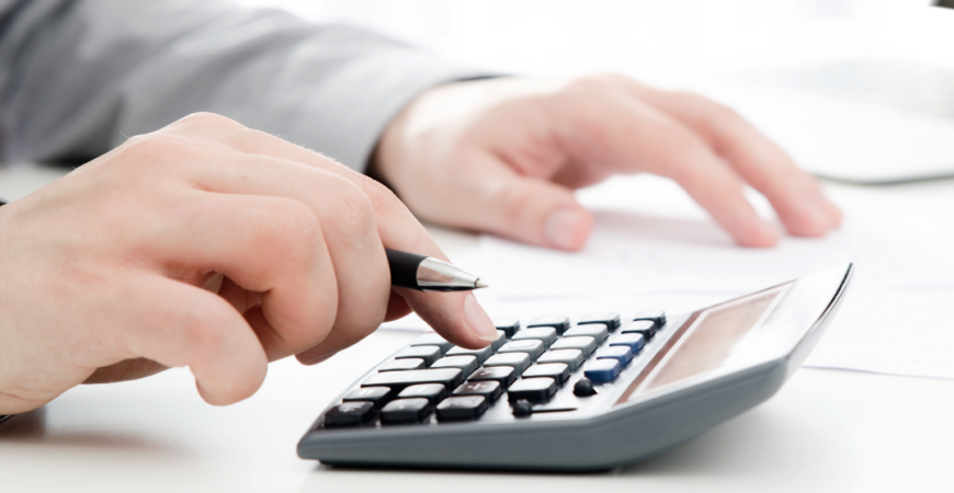Advogado calculando custos de inventário em Praia Grande SP utilizando calculadora e documentos sobre mesa de escritório.
